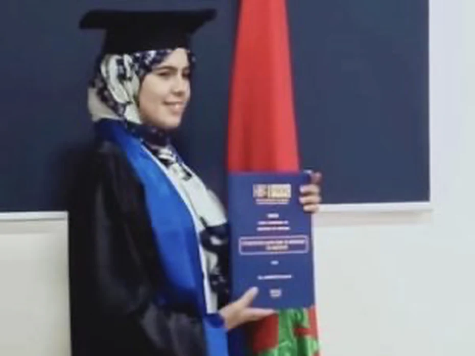 Une diplômée de l'association présente son diplôme devant le drapeau marocain